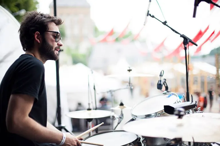Antoine Valvin à la batterie en plein air, sous les drapeaux d’un festival